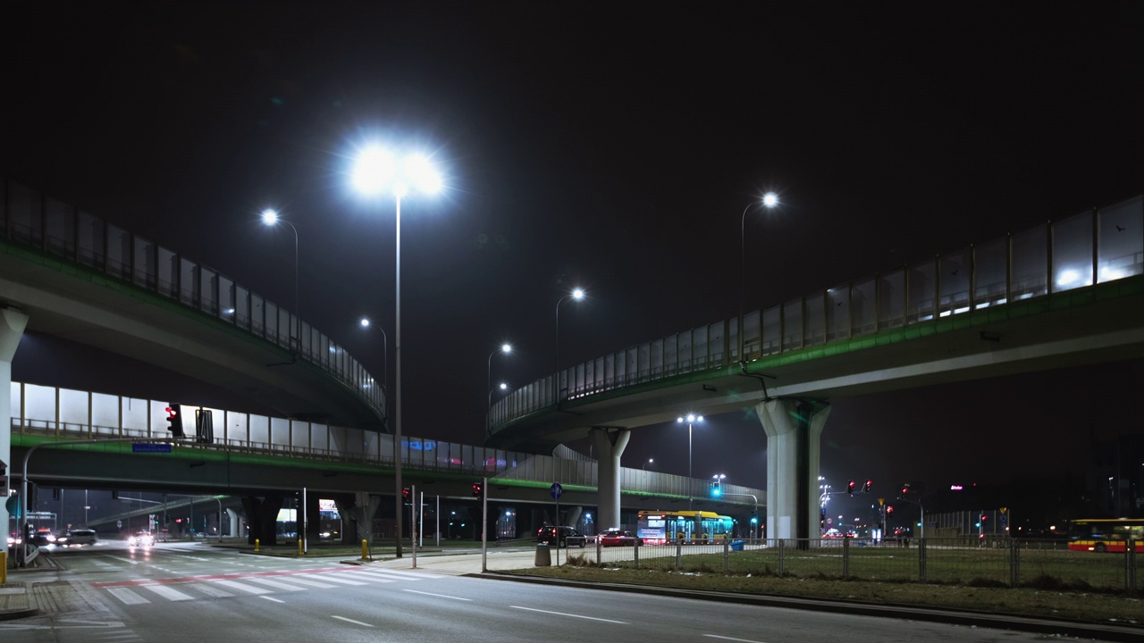 时间交错的交通交汇处在晚上，现代的道路交叉口在晚上华沙市。汽车在高速公路交叉口快速行驶。多层高速公路的延时镜头视频素材