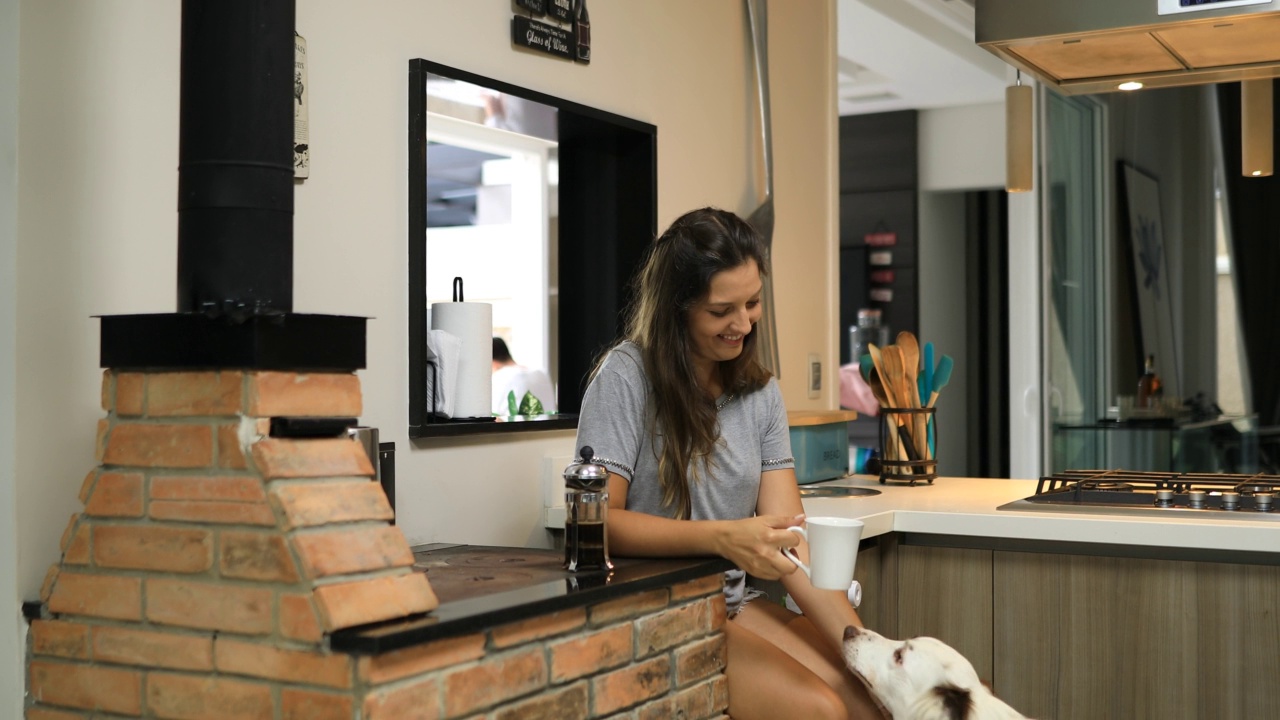 女人在家喝咖啡，抚摸着边境牧羊犬视频素材