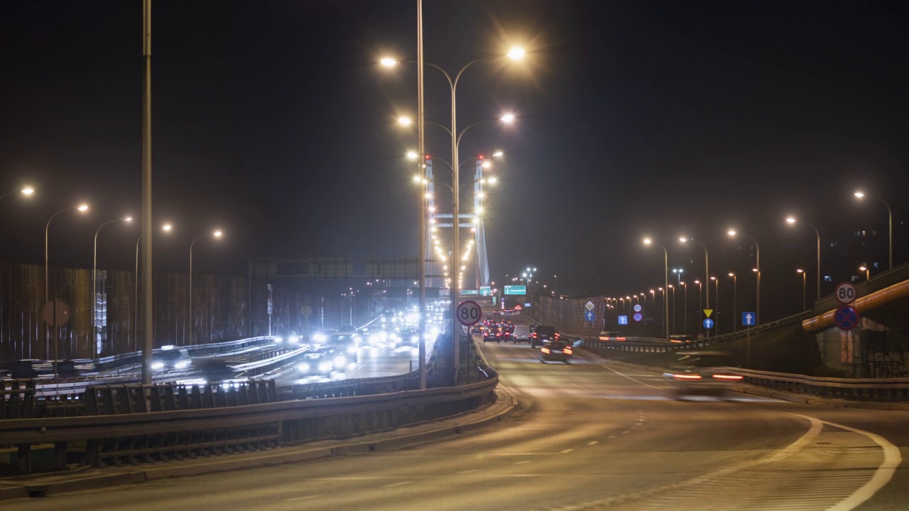 时间的推移，夜晚的交通道路上，快速运动的汽车行驶在城市高速公路上，导致照明吊桥。夜晚，华沙的现代化高速公路。光迹长曝光视频素材