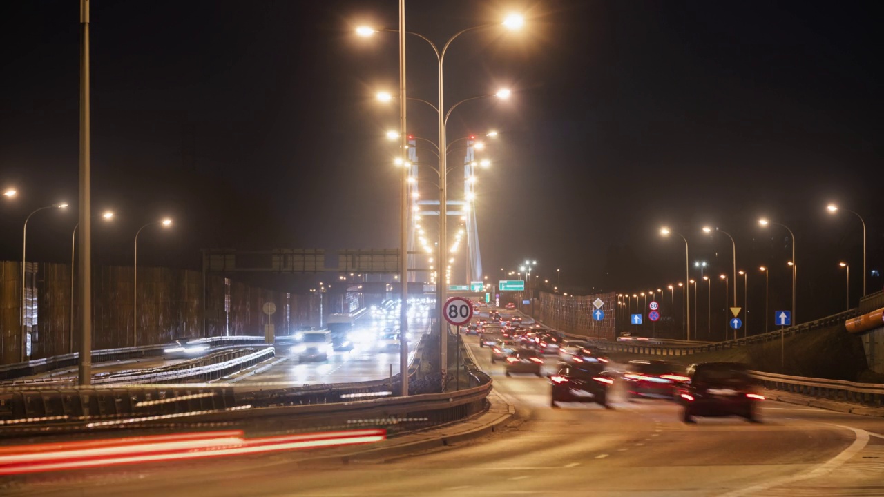 时间的推移，夜晚的交通道路上，快速运动的汽车行驶在城市高速公路上，导致照明吊桥。夜晚，华沙的现代化高速公路。光迹长曝光视频素材