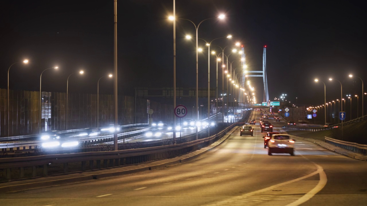 时间的推移，夜晚的交通道路上，快速运动的汽车行驶在城市高速公路上，导致照明吊桥。夜晚，华沙的现代化高速公路。光迹长曝光视频素材