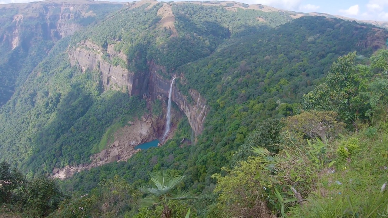 孤零零的瀑布从山顶坠落，从山顶角度依偎在绿色的森林中视频素材