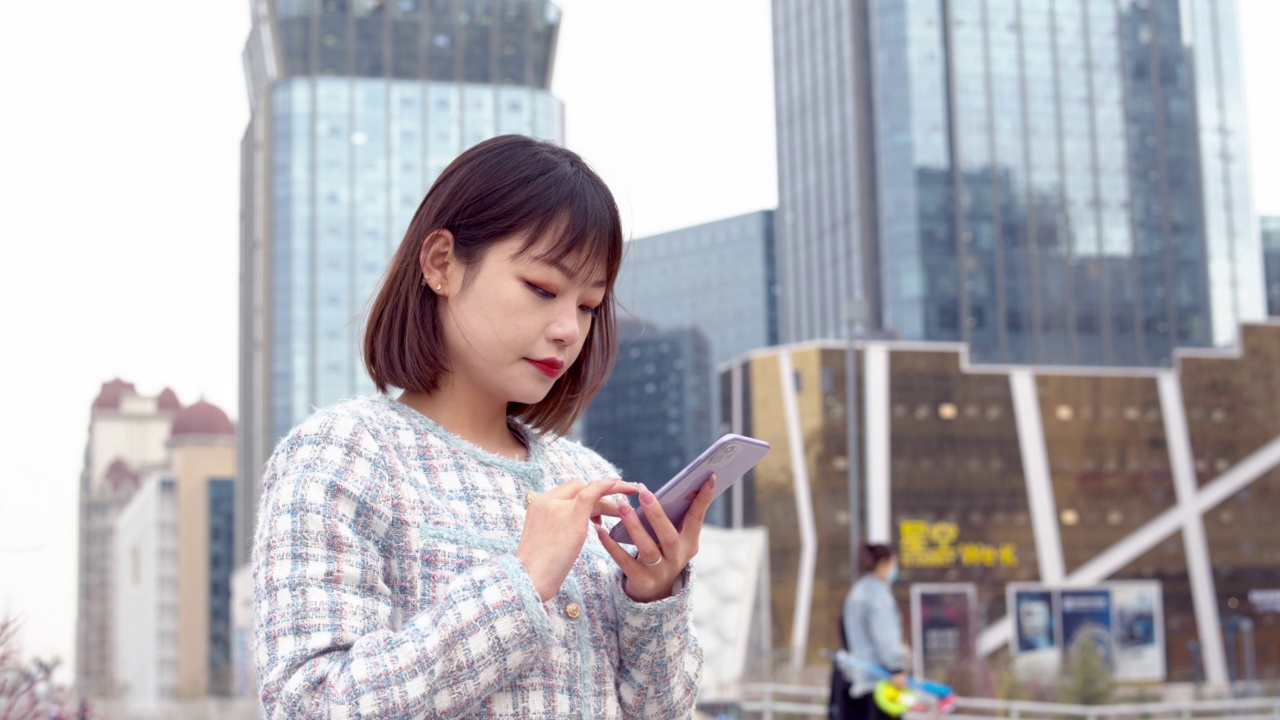 亚洲年轻女子在城市街道上使用智能手机视频素材