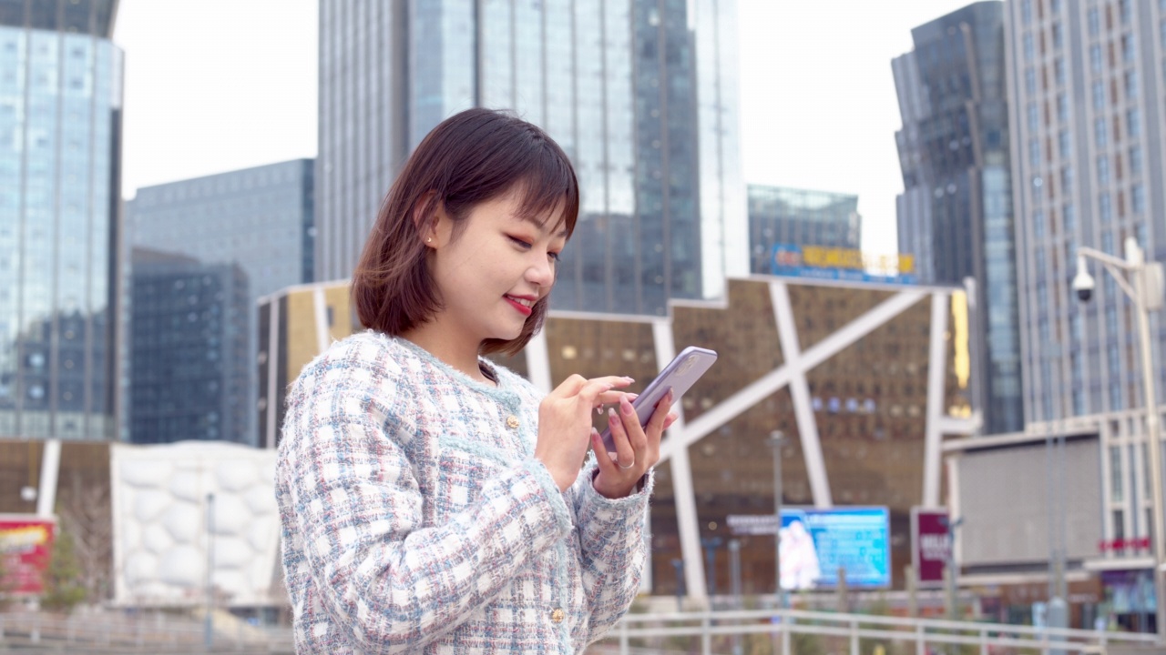 亚洲年轻女子在城市街道上使用智能手机视频素材