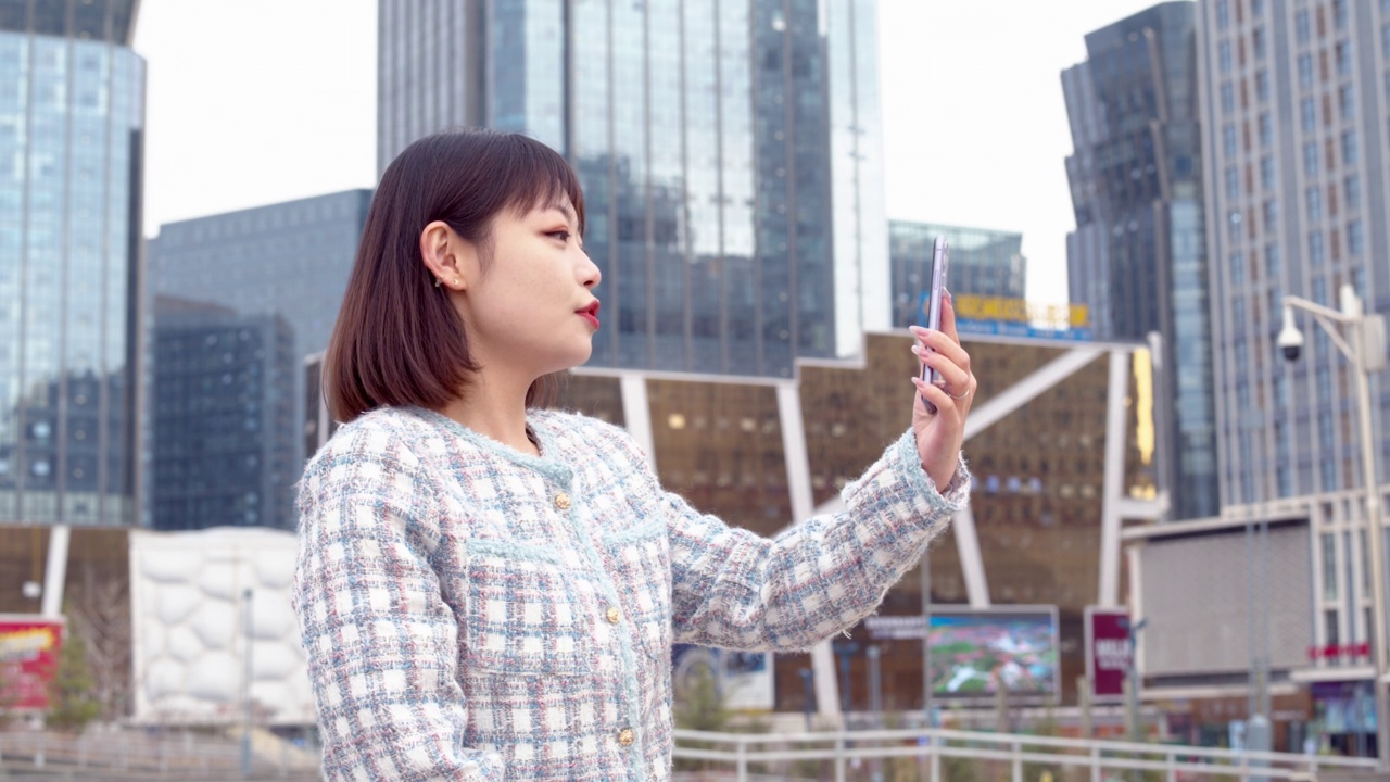 亚洲年轻女子在城市街道上使用智能手机视频素材