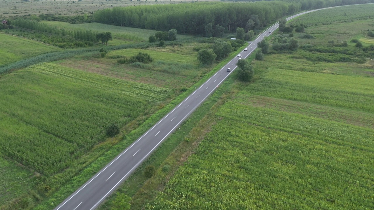 道路上的交通通过绿色的夏季景观，无人机pov视频素材