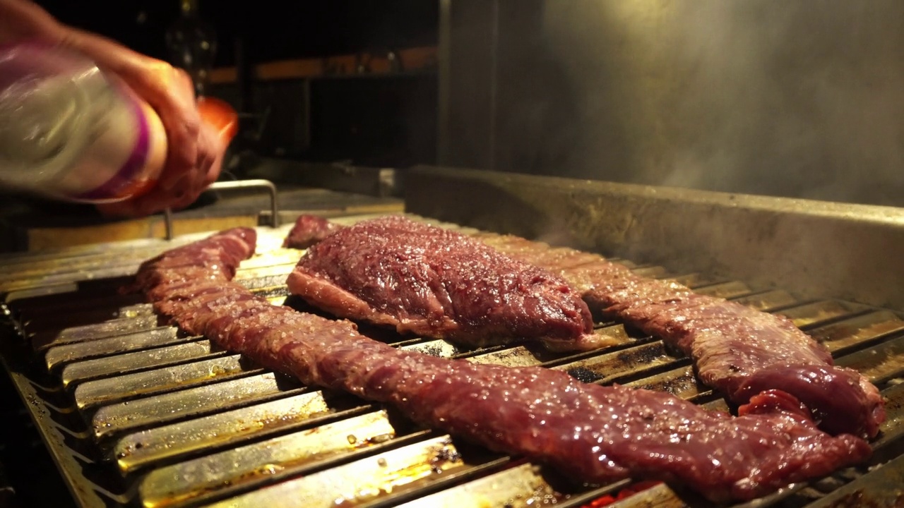 在4k的夜间，在各种排骨和烤肉上撒海盐的特写调味视频素材