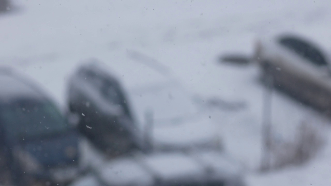 冬天白天会下大雪。在雪旋风中，汽车被雪覆盖。窗外飘着雪花。选择性对焦，景深浅视频素材