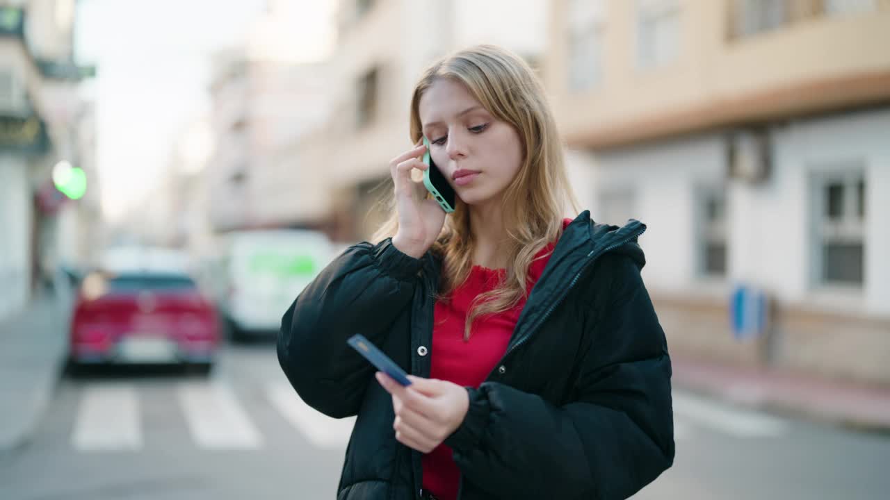 年轻的金发女孩在街上用手机聊天，刷信用卡视频素材