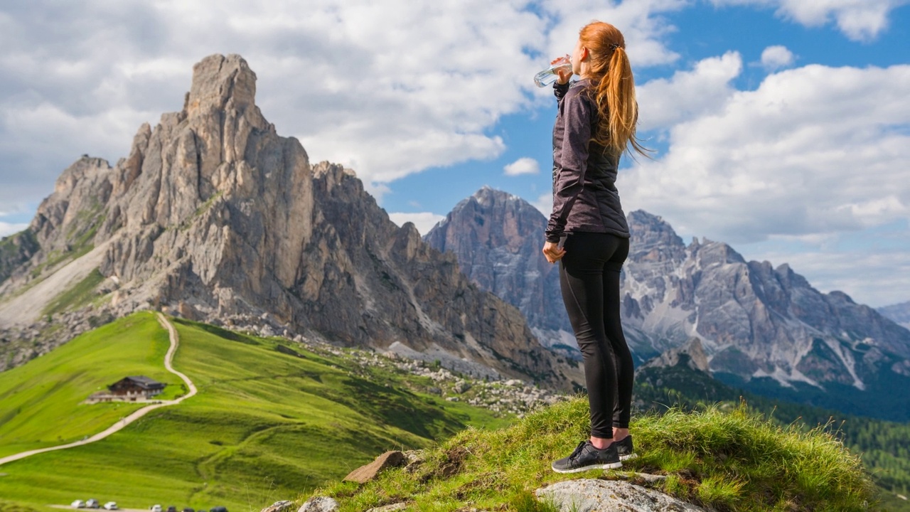 在山中徒步旅行后休息的女人，用水瓶喝水视频素材