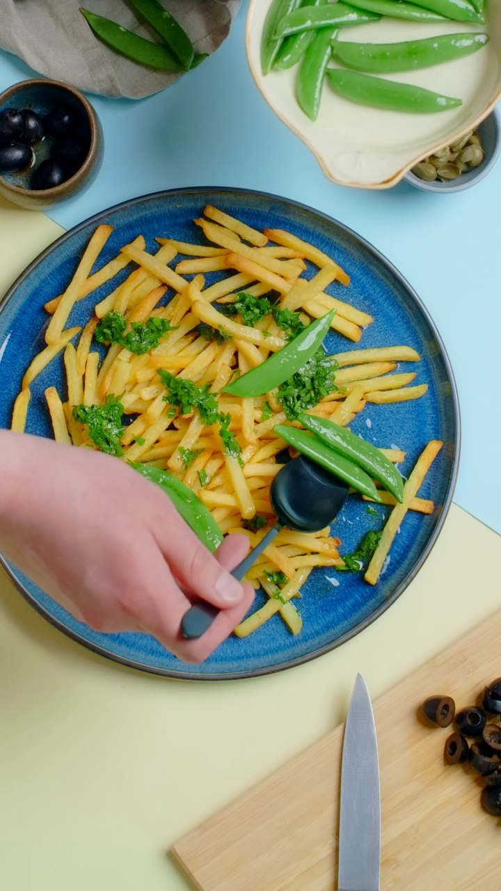 垂直桌面视频:厨师添加甜豌豆荚油炸土豆菜视频素材