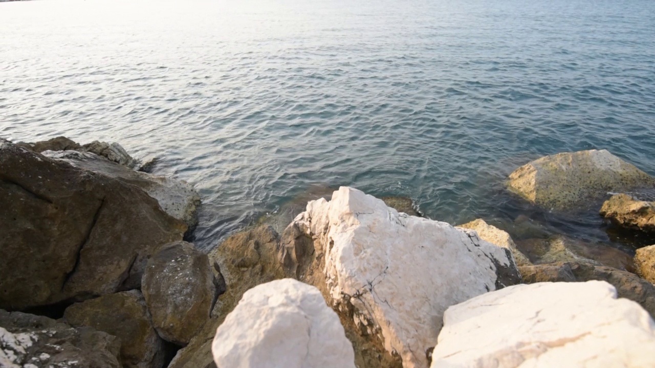 拂晓的海边，海浪拍打着岩石嶙峋的海堤视频素材