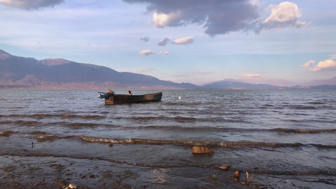 湖上的渔船和蓝山的背景。夕阳光视频下载