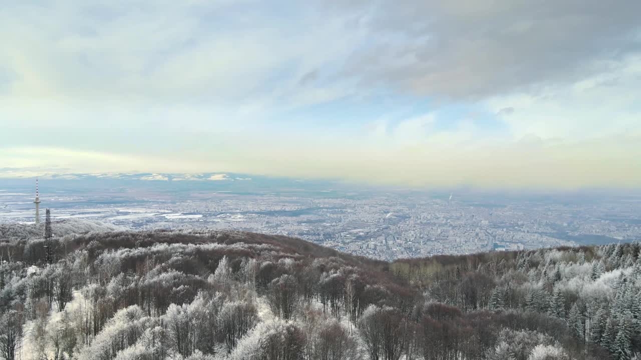 从空中俯瞰山脉、电视塔和城市的冬季景色。多云的天空。视频素材