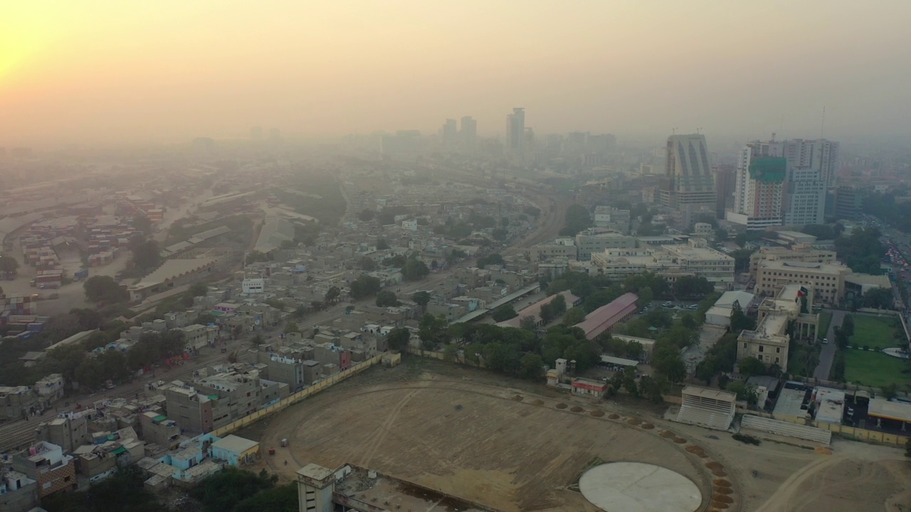 在浓密的雾霾中，在繁忙的市中心建筑和交通上方的空中平移——巴基斯坦卡拉奇视频素材