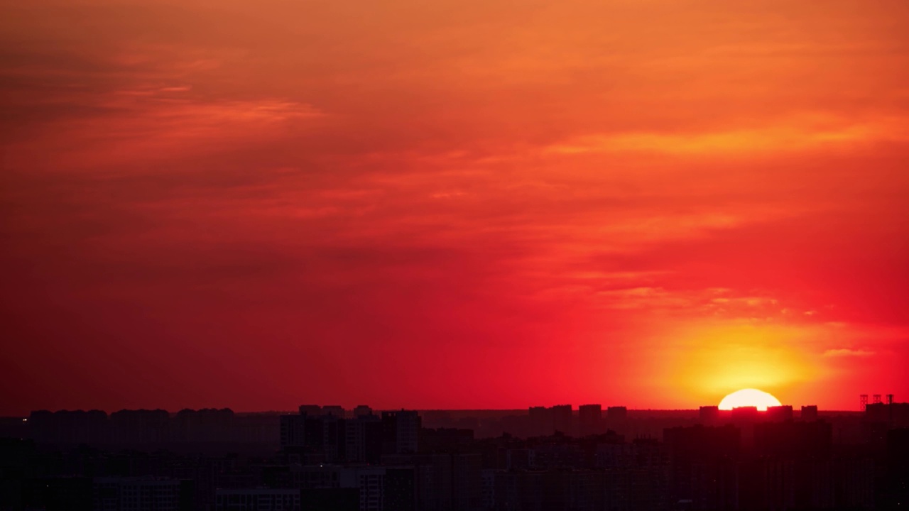 夕阳在红色的天空与晚霞在城市。夕阳西下，照耀着城市的高楼大厦，时间流逝视频素材