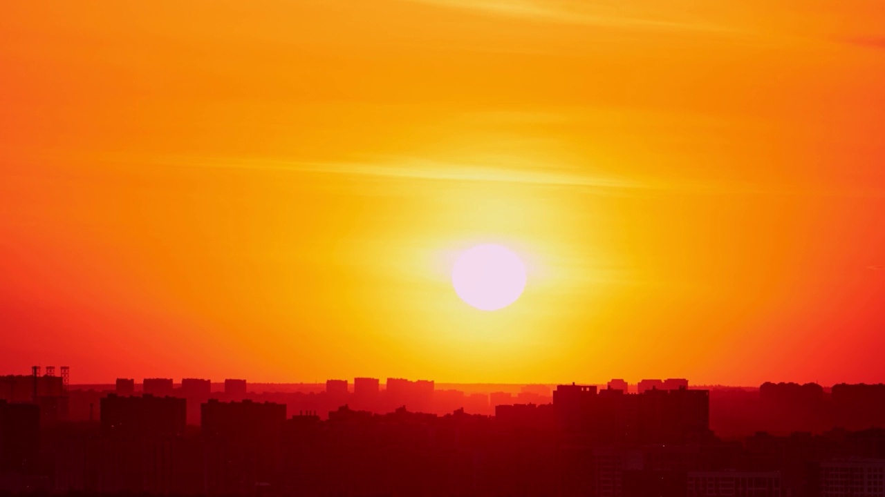 清晨的天空在黎明时分伴随着一轮巨大的太阳升起在城市上空，日出的时间流逝视频素材