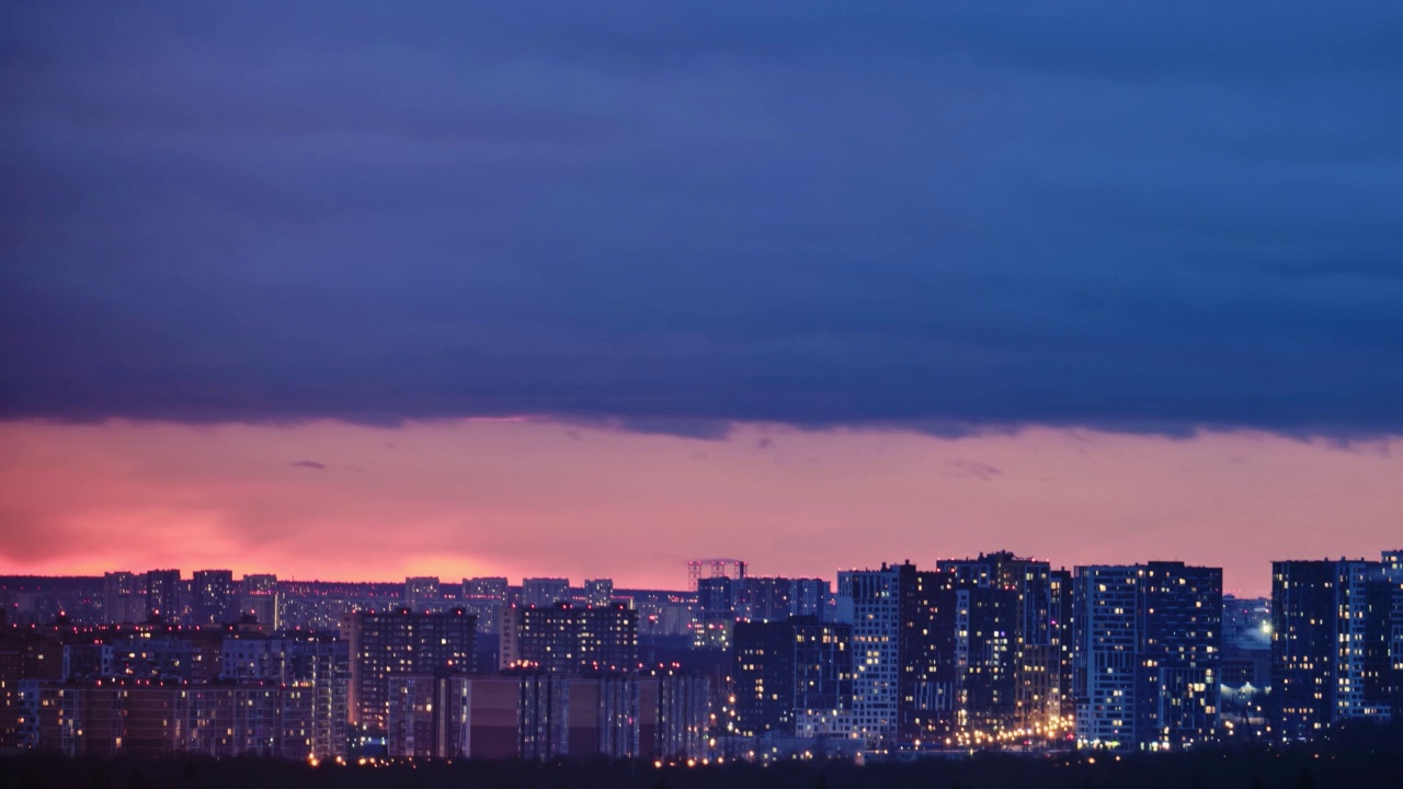 夜晚的雷雨云笼罩着高楼大厦，时间流逝。夜晚的城市上空乌云密布，引人注目视频素材