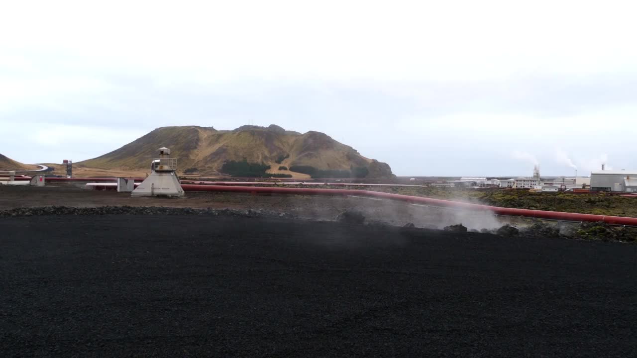 冬季多云天气，冰岛雷克雅尼半岛Grindavík附近的Svartsengi地热发电厂前，用蒸汽输送热水的红色管道。视频下载