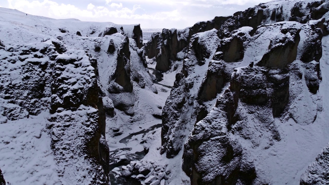 冰岛南部著名的峡谷Fjaðrárgljúfur，靠近1号公路，被雪覆盖的岩石，陡峭的悬崖和蜿蜒的Fjaðrá河。视频下载