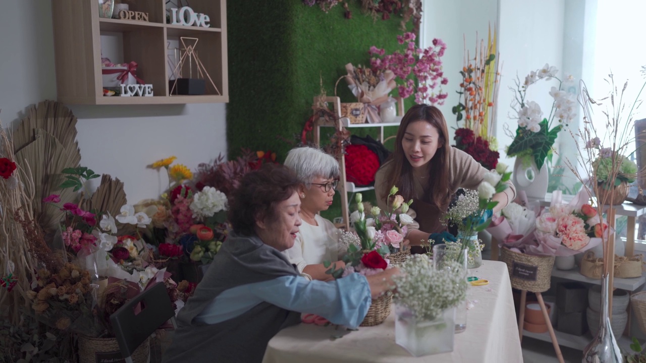 亚洲华人女花商教她的高级成年学生插花在花店视频素材画面2