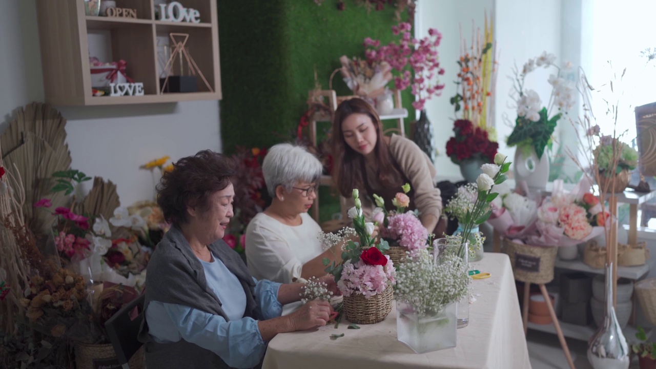 亚洲华人女花商教她的高级成年学生插花在花店视频素材画面4