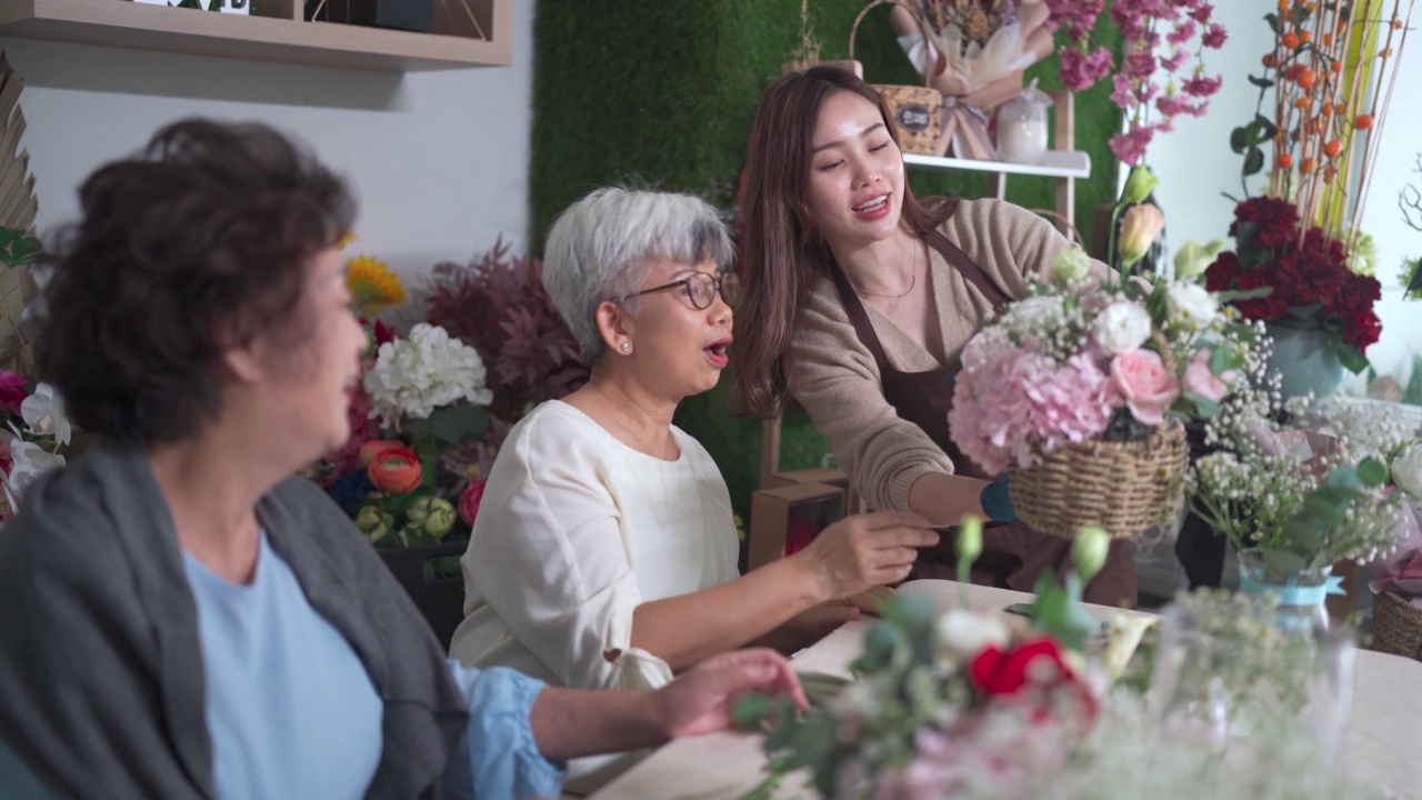 亚洲华人女花商在她的工坊班向她的成年高年级学生展示插花视频素材画面3