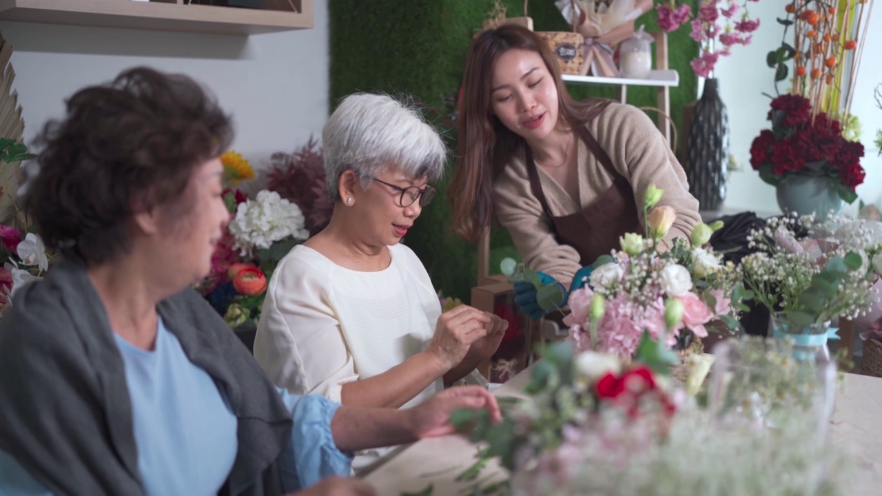 亚洲华人女花商在她的工坊班向她的成年高年级学生展示插花视频素材画面4