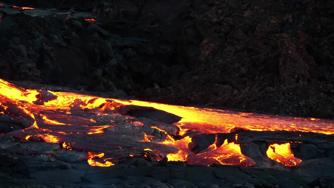 冰岛西南部雷克雅尼半岛，Fagradalsfjall山附近的Geldingadalir山谷火山爆发的景象，在黑暗中流淌着发光的熔岩河。视频下载