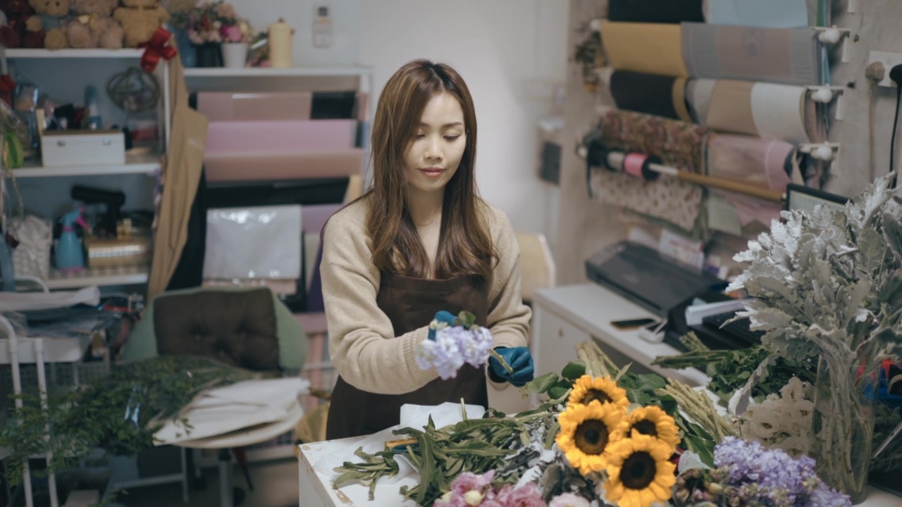 亚洲华人女花商，小企业主在花店切割和安排花束。日常经营小生意视频素材画面4