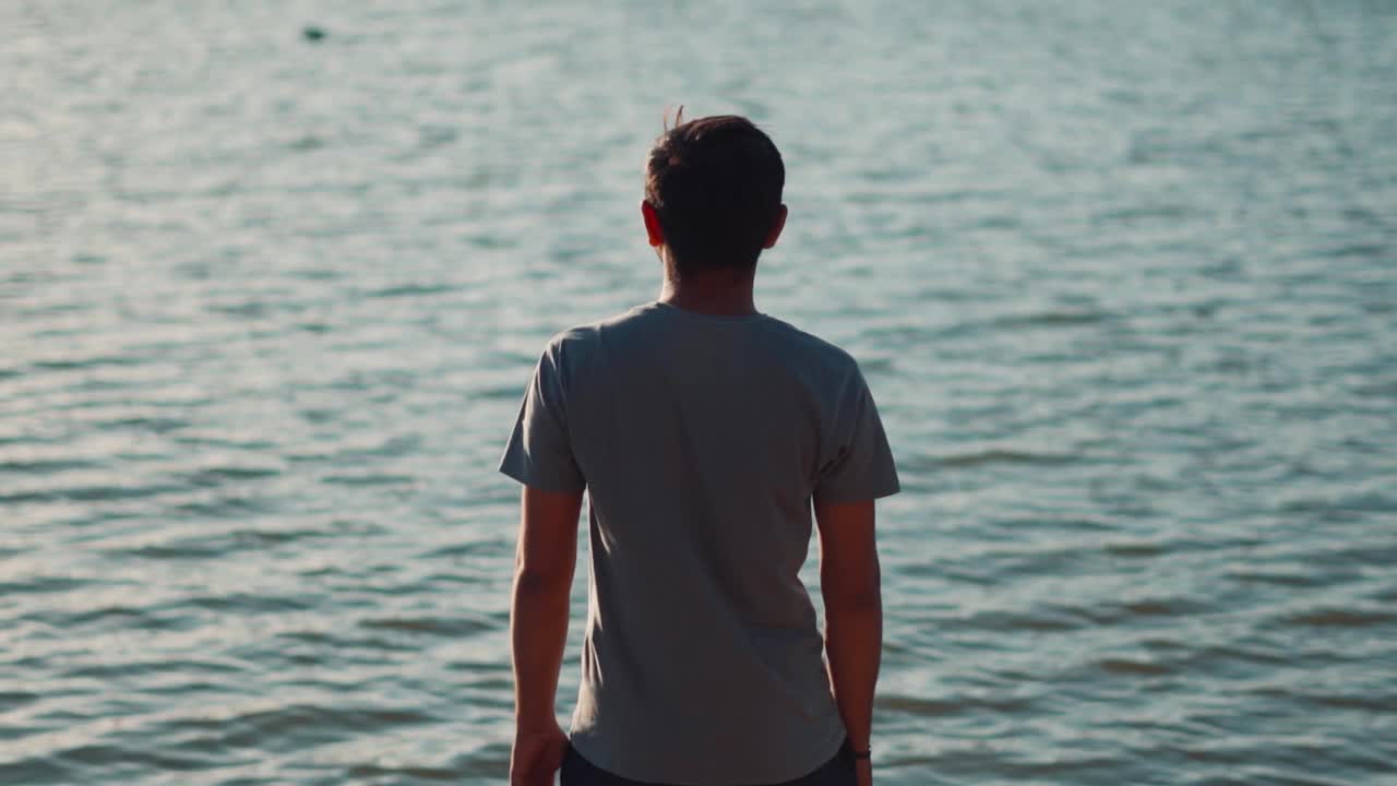 一个印度人凝视着湖水的后视图肖像。男人盯着湖水。旅行背景与拷贝空间视频素材