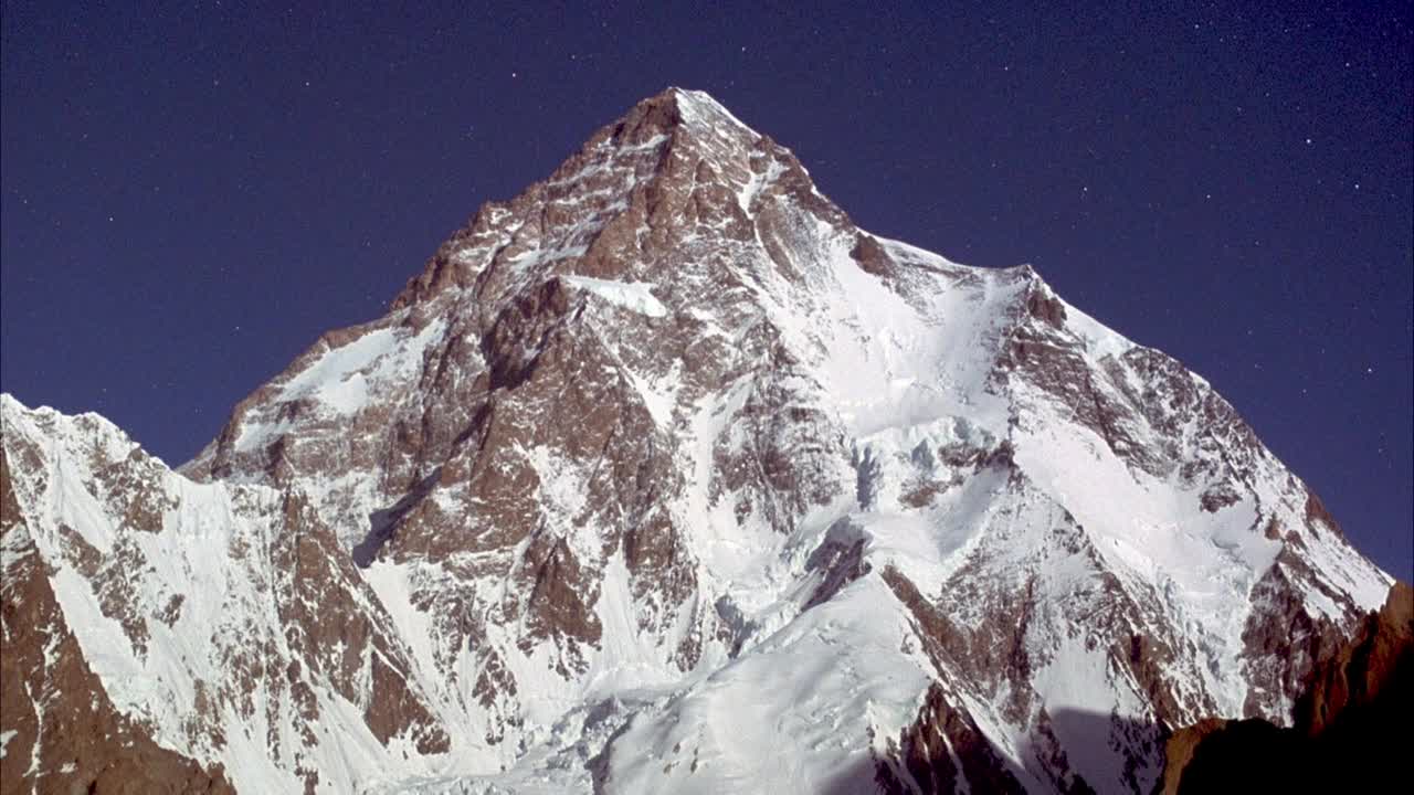 雪峰夹角中覆岩山。可能是K2。看到轻云或轻烟快速从左向右吹。在背景中看到清澈的蓝天。视频素材