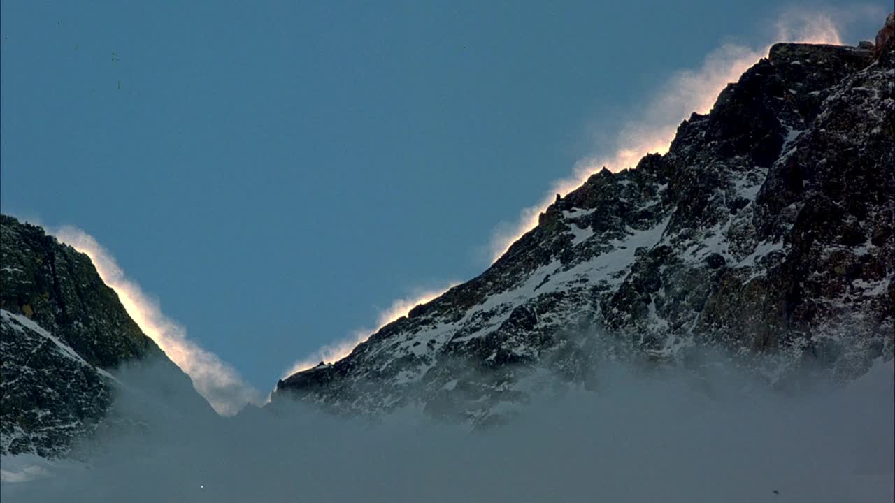 中角建立雪山。当雪融化时，山脉开始冒蒸汽。在背景中看到晴朗的天空。视频素材