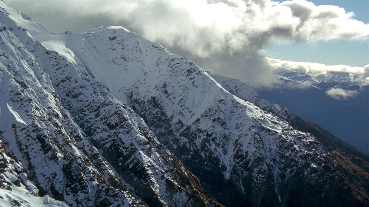 积雪覆盖的山脉。在山顶看到积雨云。参见背景山脉。视频素材