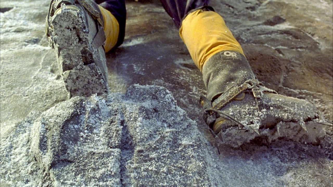 当登山者被压在白雪覆盖的灰色岩壁上时，登山靴在壁架上的闭合角度。看到雪崩的降雪和左边靴子滑作为窗台断裂。看到一块岩架朝下，挡住pov。行动。视频素材