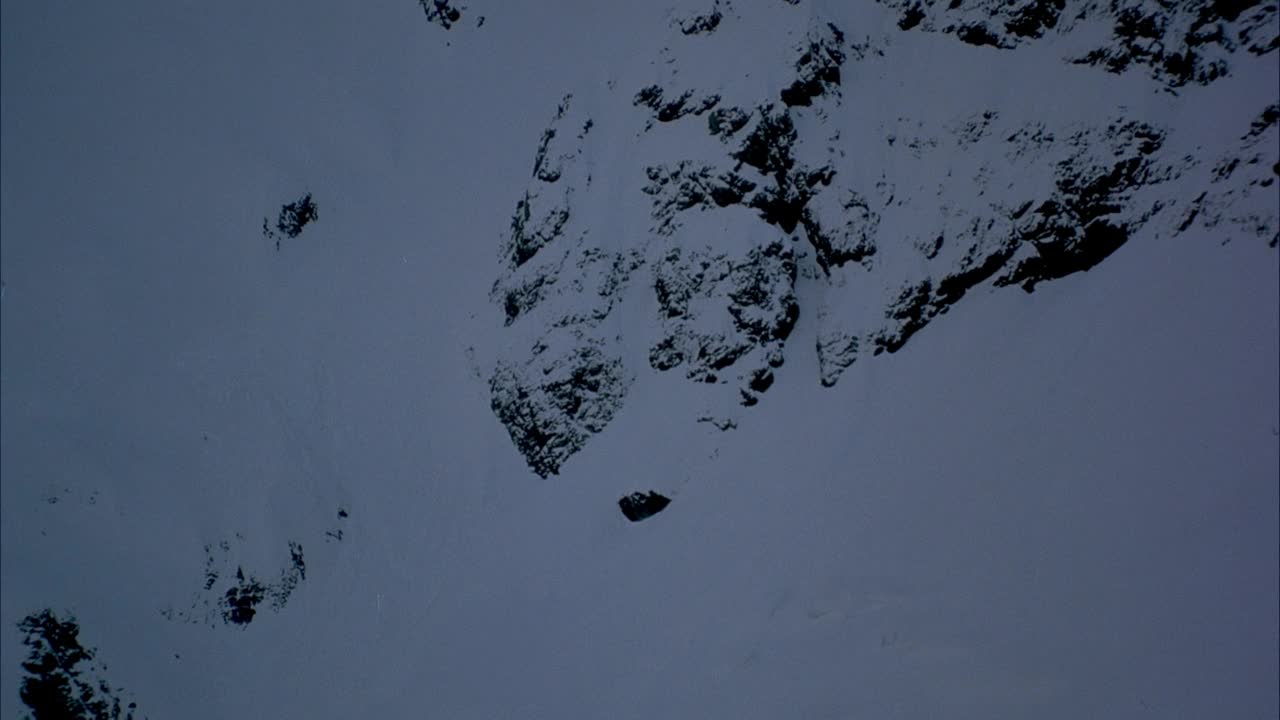 白雪覆盖的山坡上的天线。在两个较小的山峰之间的间隙飞向雪山与高峰。可能是K2。视频素材