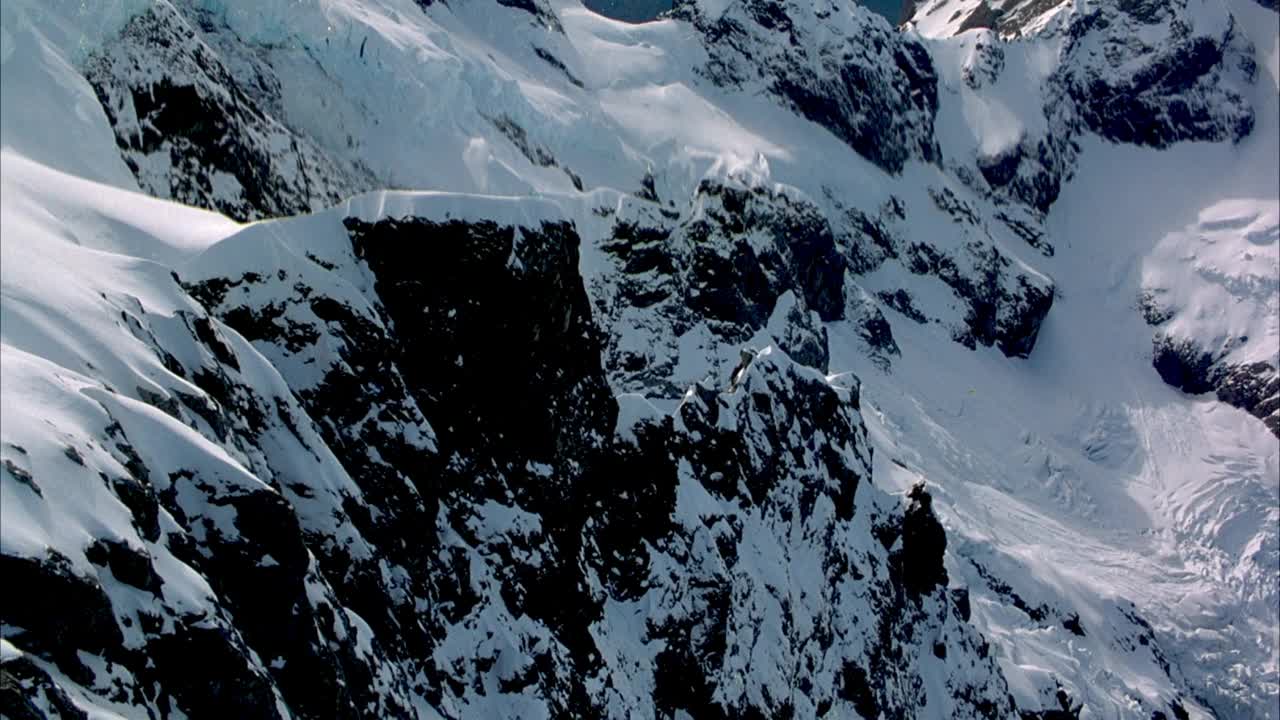 在雪山上空盘旋。放大并聚焦于边缘脊或arete。后面是白雪覆盖的山坡。当pov向上拉并绕着山脊逆时针飞行时，集中在山脊上。往后看，整个山脊和雪山斜坡的背景。云视频素材