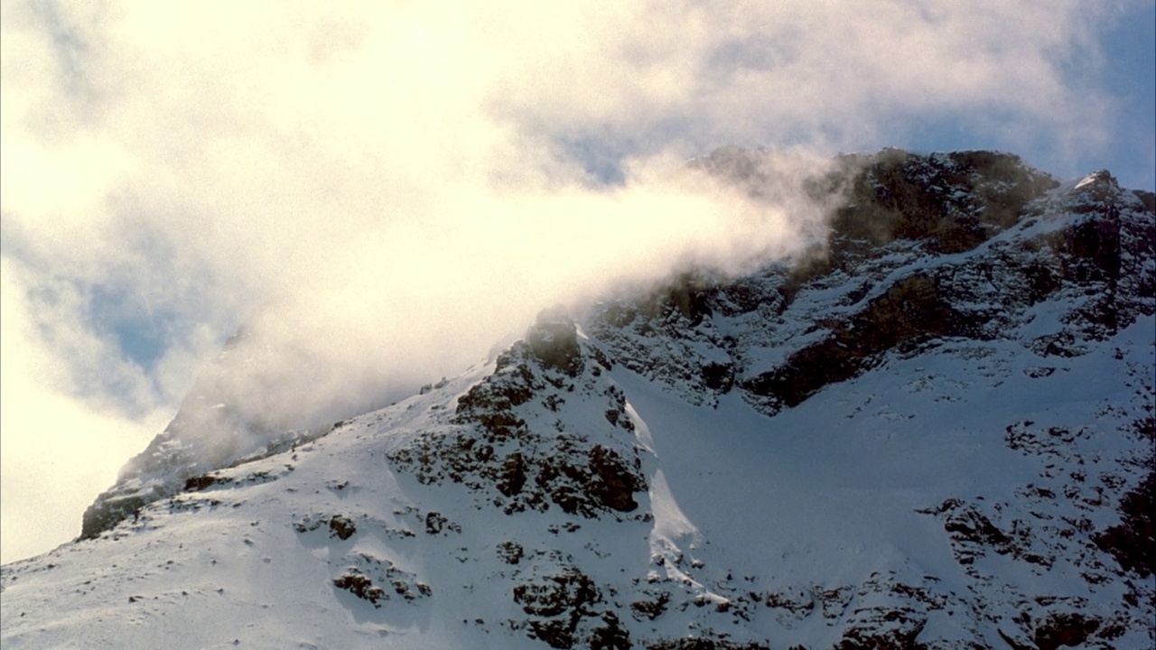 雪山山峰的中等角度。看一层云从左向右漂移。视频素材