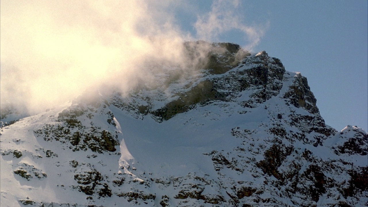 雪山山峰的中等角度。看一层云从左向右漂移。视频素材