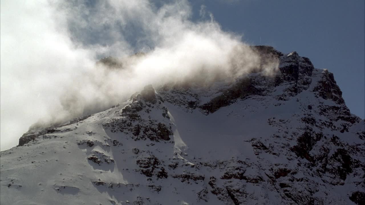 雪山山峰的中等角度。看一层云从左向右漂移。视频素材