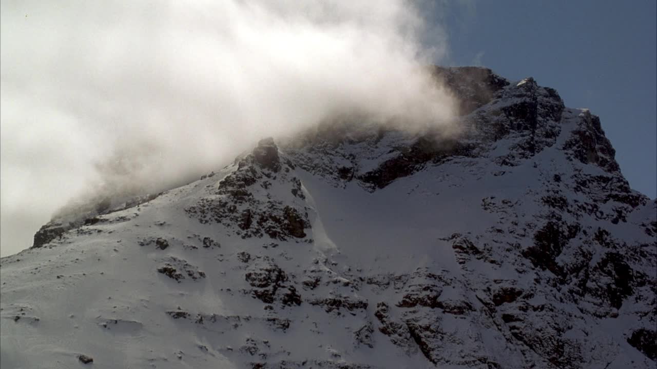 雪山山峰的中等角度。看一层云从左向右漂移。视频素材