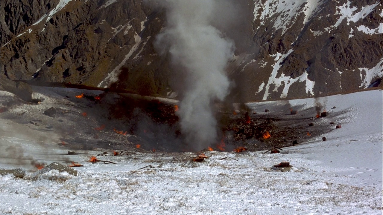 中等角度的闷烧大灰色火山口在雪中形成的前一次爆炸。看到白色的烟雾从火山口中心喷出，而深色的烟雾从闷烧和燃烧的碎片中升起，散落在火山口周围。从地面看到三次爆炸视频素材