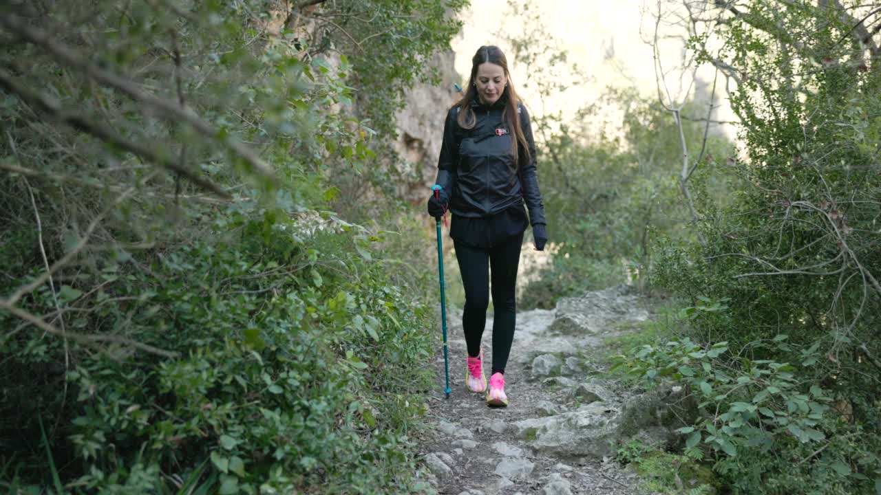 一个美丽的女人走在一条徒步旅行的小径上。视频素材