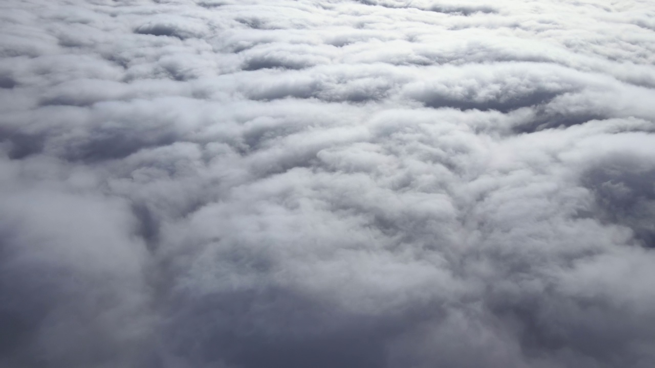 高空飞机窗口鸟瞰图，地面覆盖着暴雨前形成的蓬松积云视频素材