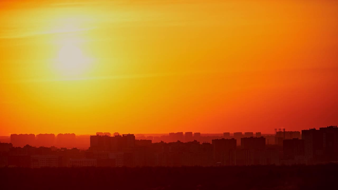 夕阳在红色的天空与晚霞在城市，时间流逝。落日照耀着高楼林立的城市视频素材