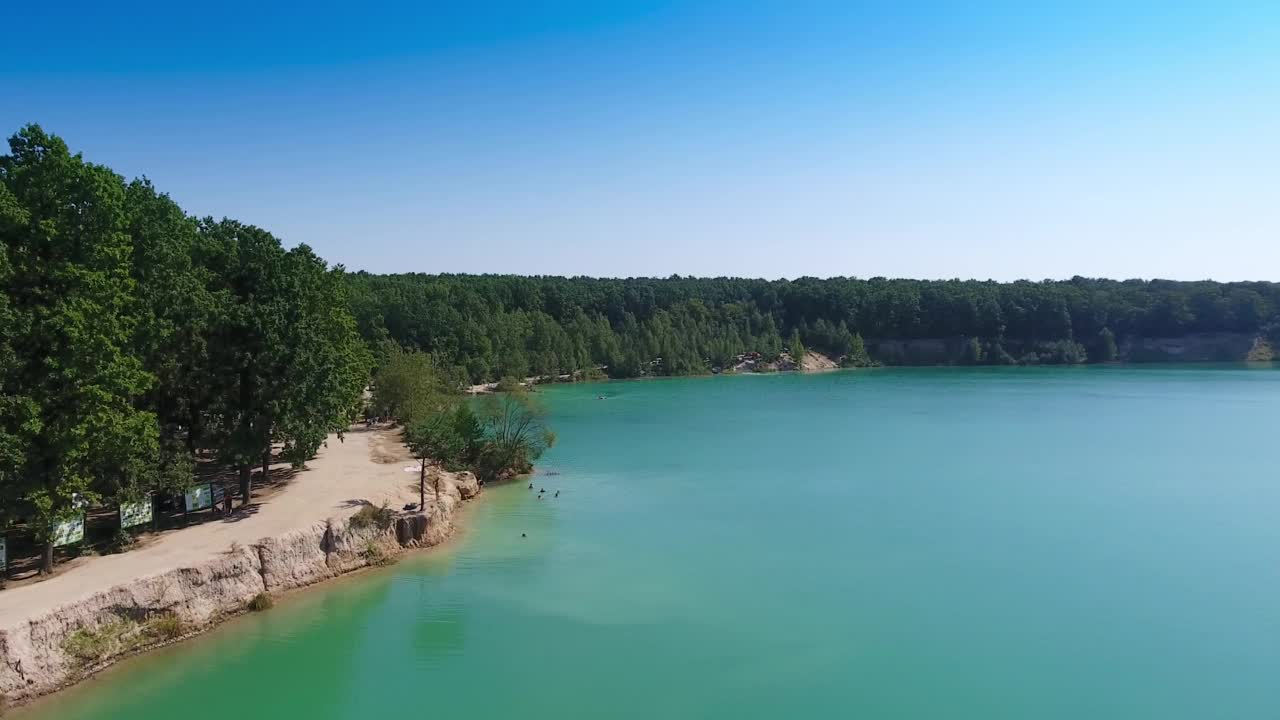 人迹罕至的湖景。蓝色的人造池塘在以前的采石场和河岸长满了树木。视频素材