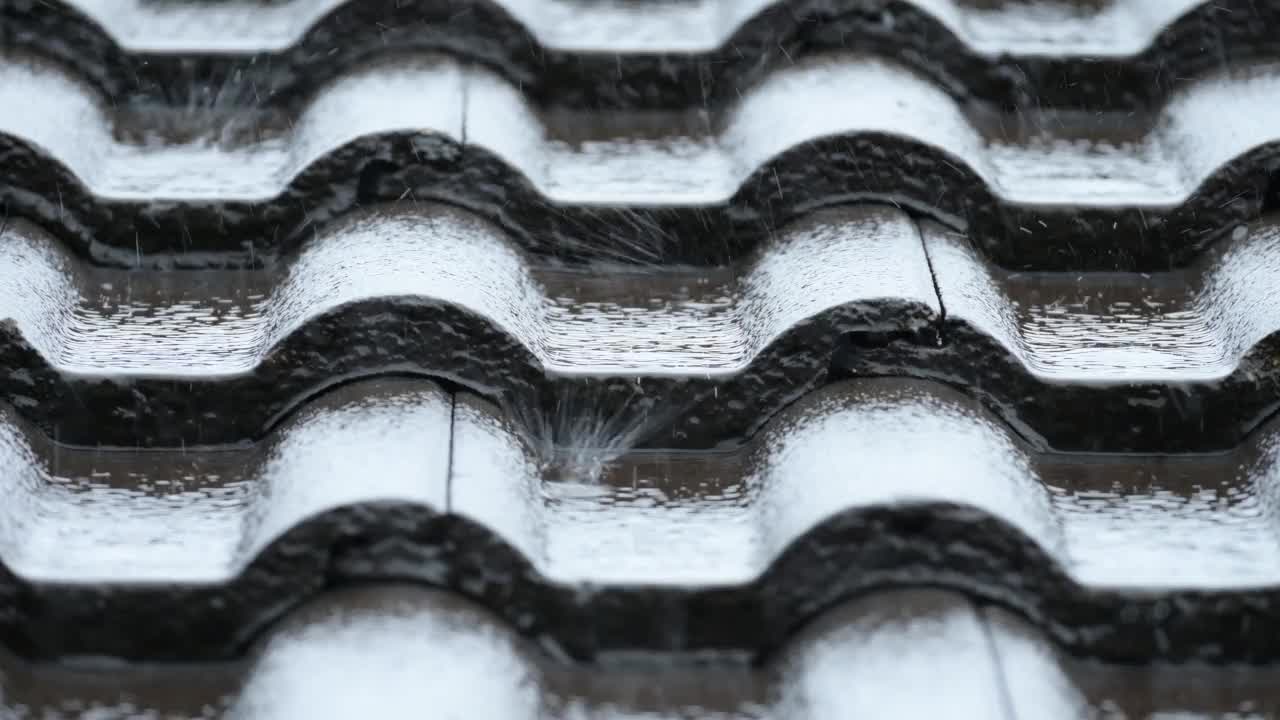 雨季，大雨滂沱，雨水倾盆而下，倾泻在黑瓦屋顶的房子上视频素材