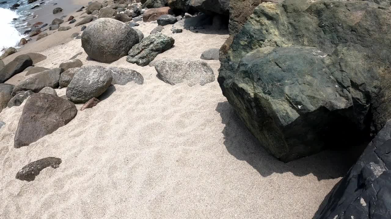 波夫沿着岸边的岩石、沙滩和海浪之间奔跑，在白天的海边驰骋视频素材