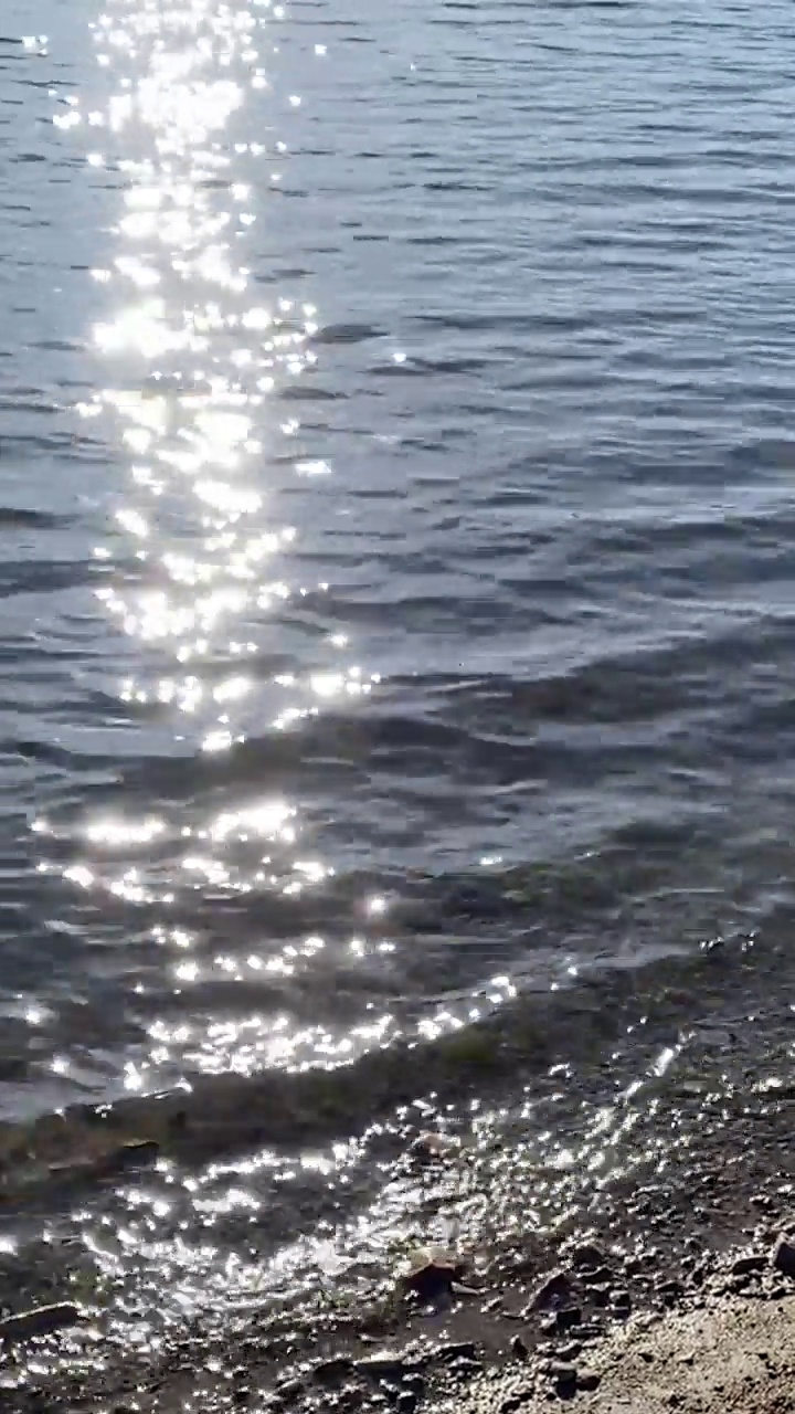 垂直日落阳光海滩波浪海边海岸波浪阳光闪耀闪亮的太阳反射水多风的海洋冲浪流湖视频素材