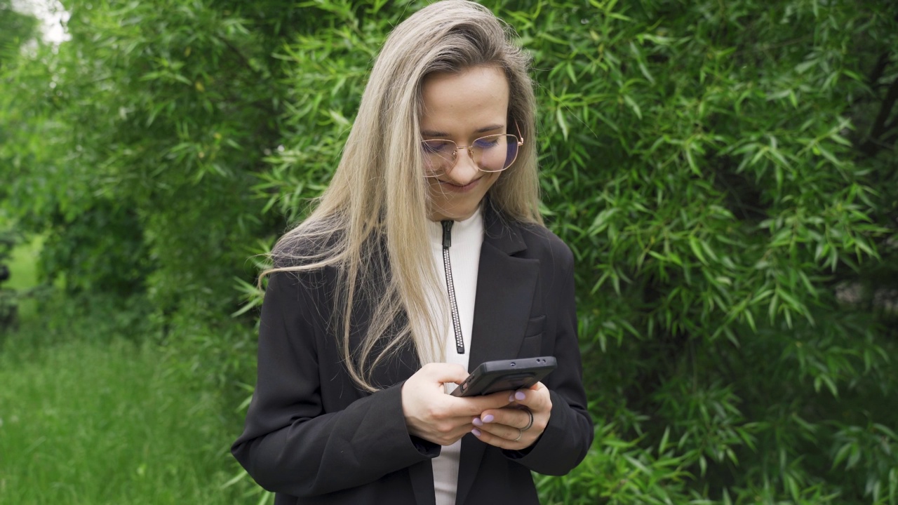 一个美丽的女人在户外用手机打字的肖像视频素材